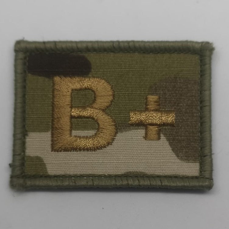 A B+ velcro patch is affixed to a soldiers body armour on his