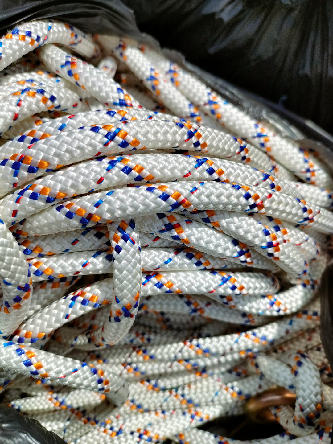 Close up shot of thick, white rope with blue and orange pattern circling around