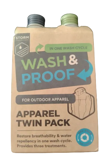 A cardboard twin-pack box for Storm Wash &amp; Proof Apparel Twin Pack, featuring a beige background with blue, green, and gray text and graphics, photographed on a dark textured surface.