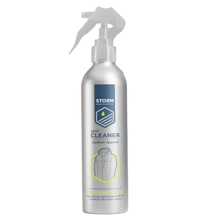 A silver spray bottle of STORM Spot Cleaner for outdoor apparel, featuring a white trigger sprayer and a blue and yellow label, set against a neutral gray background with a green &