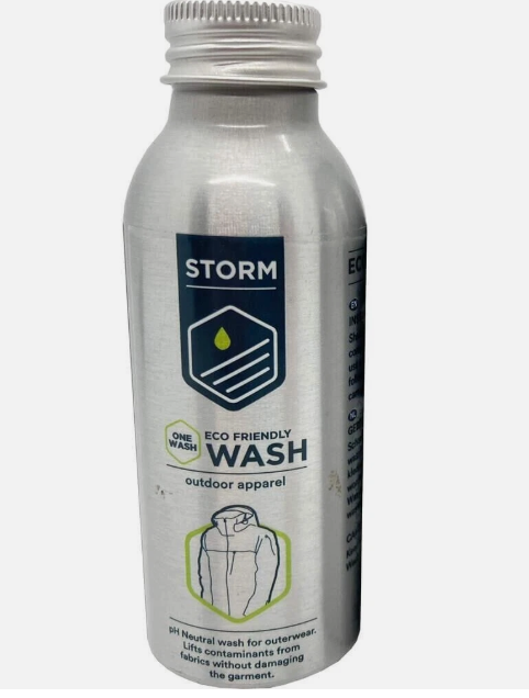 A silver bottle of STORM Eco Friendly Wash outdoor apparel one wash, featuring a dark blue and green label with a graphic of a hooded jacket.