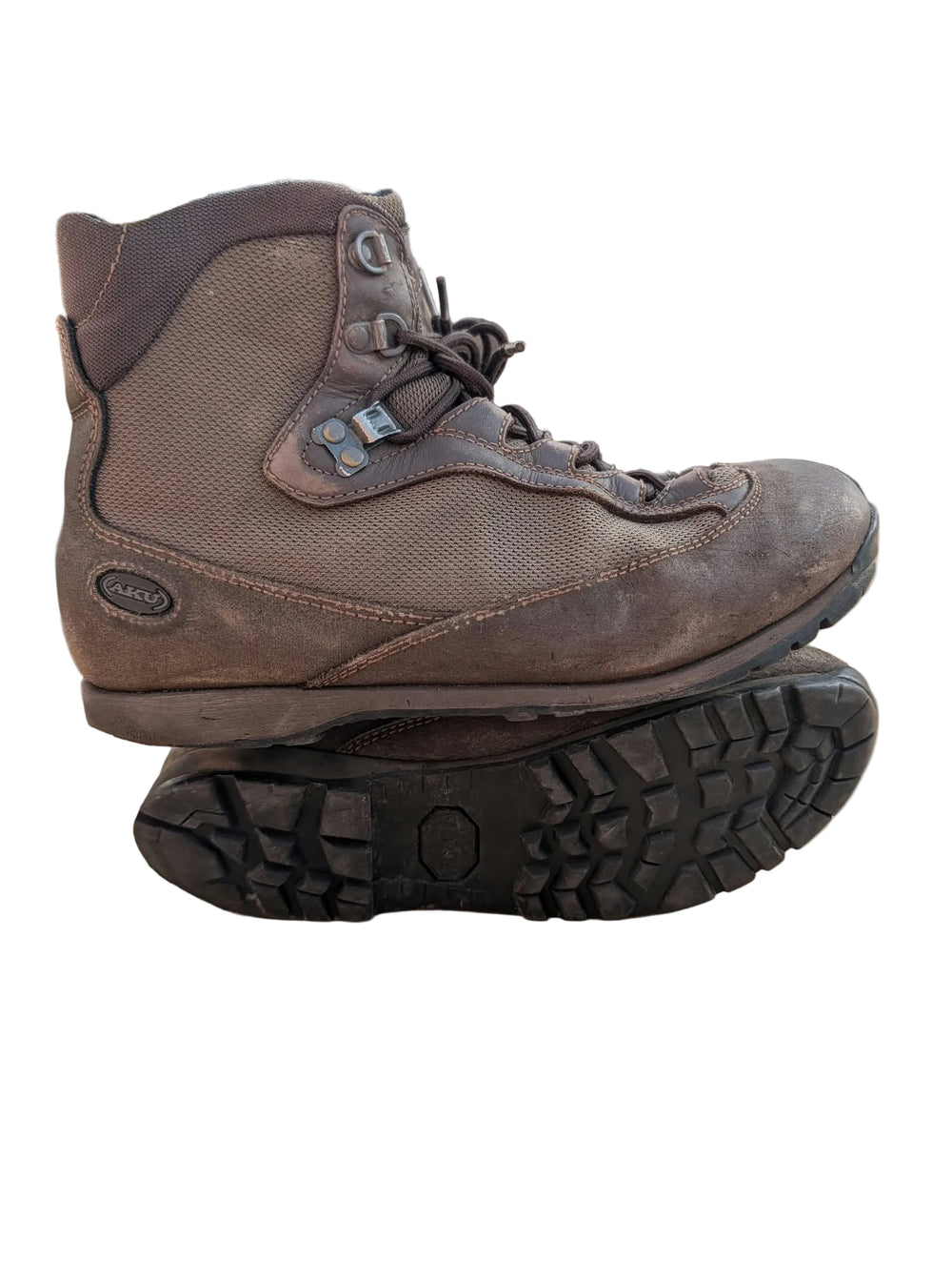 A brown Darn Tough lace-up hiking boot shown from the side, resting on top of its black treaded outsole over a cardboard surface.