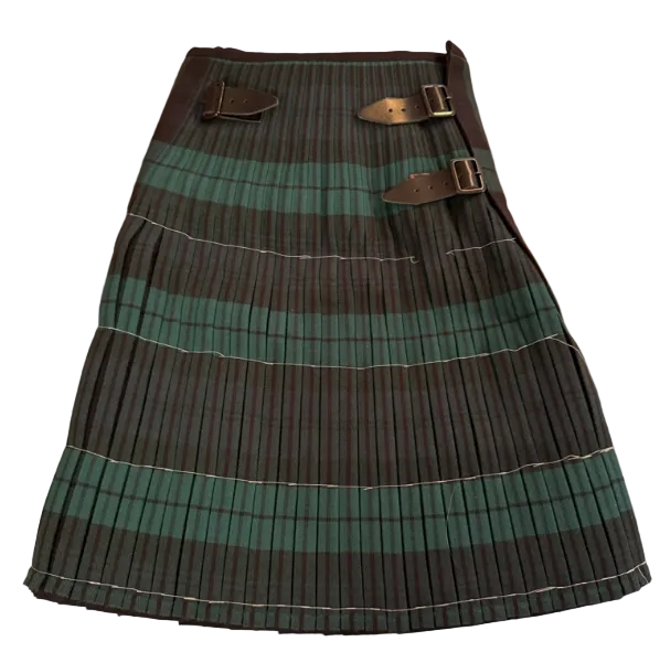 A pleated kilt in a dark green and black tartan pattern, laid flat on a wooden floor. It features a waistband with two dark leather belt loops and silver buckles.