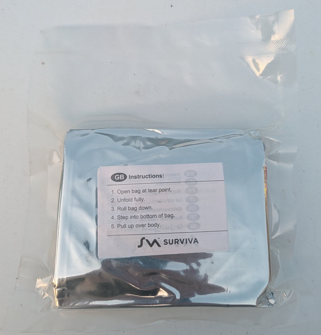 Surviva emergency blanket in a clear plastic bag on a white surface