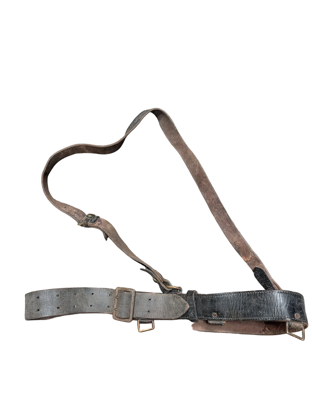 A vintage leather shoulder strap or harness belt with multiple adjustable buckles, laid flat on a textured concrete floor.