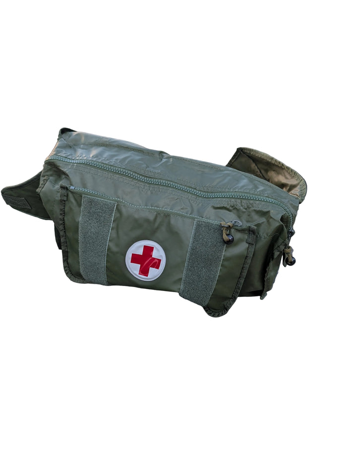 Green medical bag with a red cross on a car hood